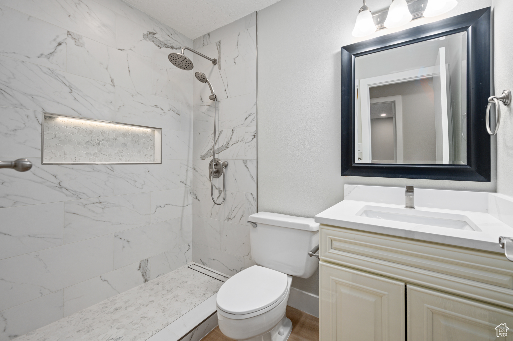 Bathroom with tiled shower, toilet, and vanity with extensive cabinet space