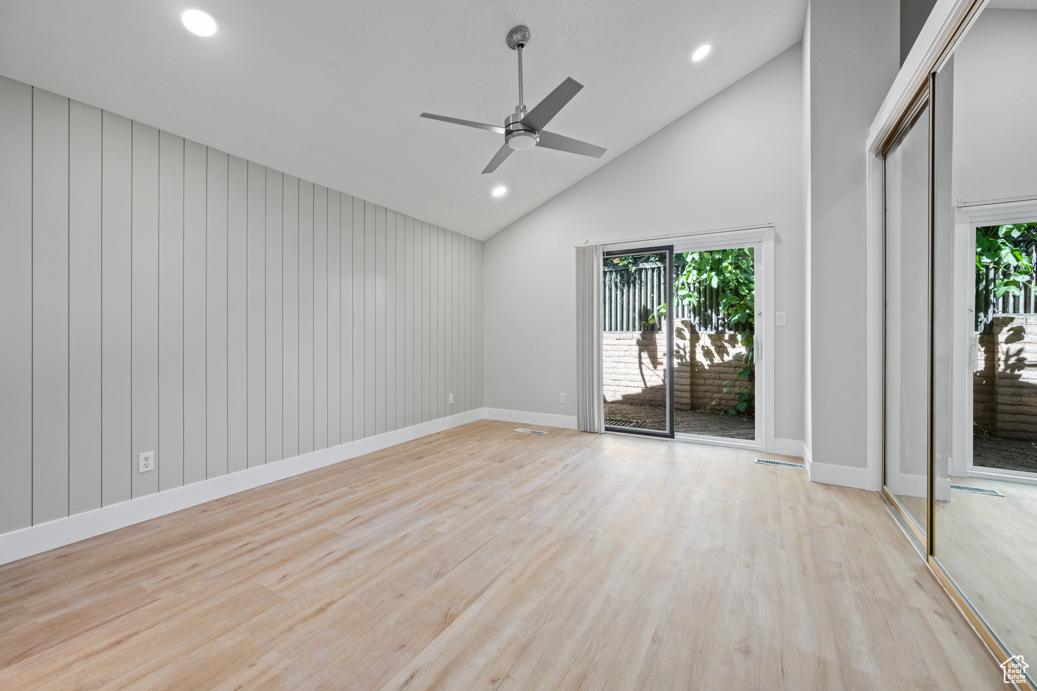 Empty room featuring high vaulted ceiling, plenty of natural light, ceiling fan, and light wood-type flooring