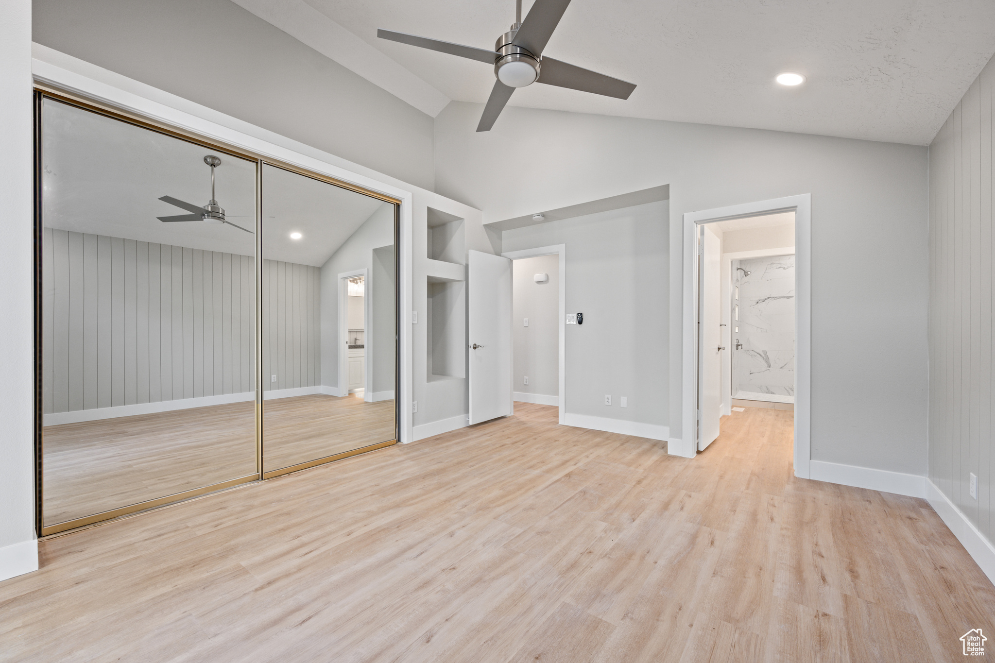 Unfurnished bedroom featuring light hardwood / wood-style floors, lofted ceiling, connected bathroom, a closet, and ceiling fan