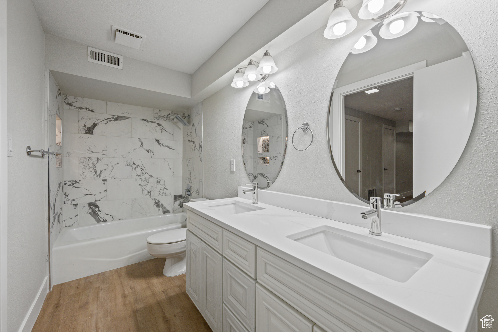 Full bathroom with hardwood / wood-style flooring, toilet, tiled shower / bath, and double sink vanity