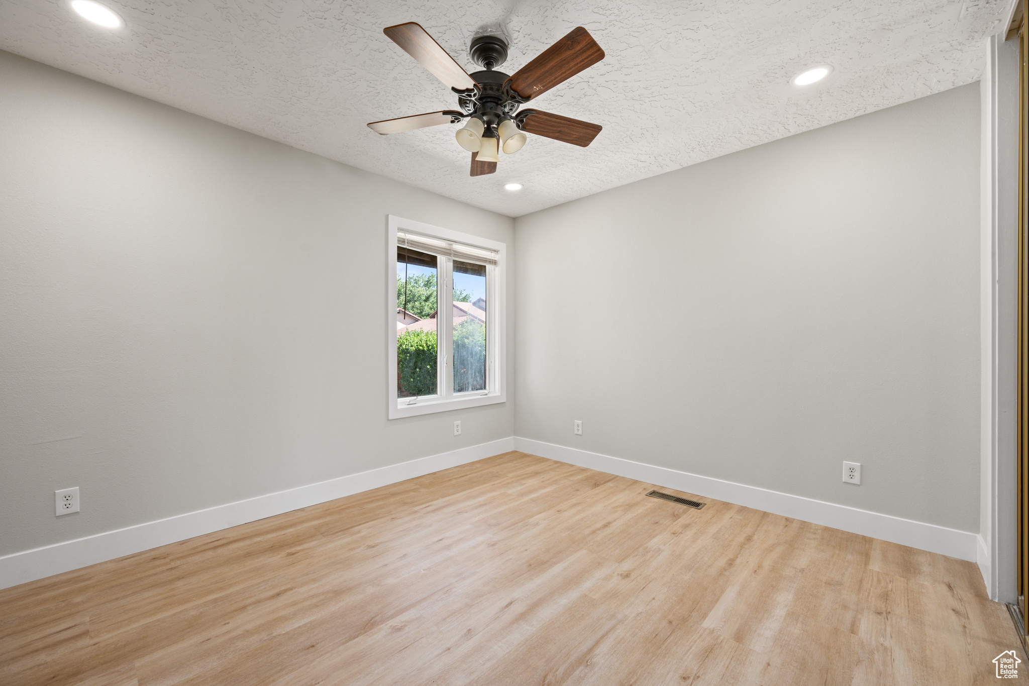 Unfurnished room featuring a textured ceiling, ceiling fan, and light hardwood / wood-style flooring