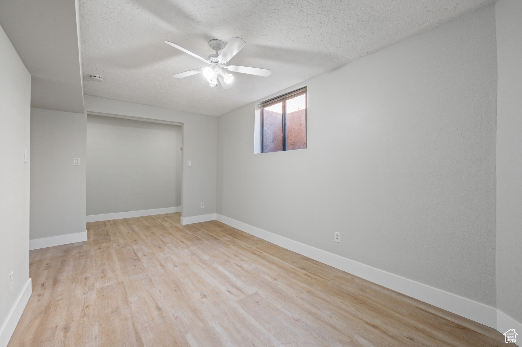 Spare room featuring ceiling fan, light hardwood / wood-style flooring, and a textured ceiling