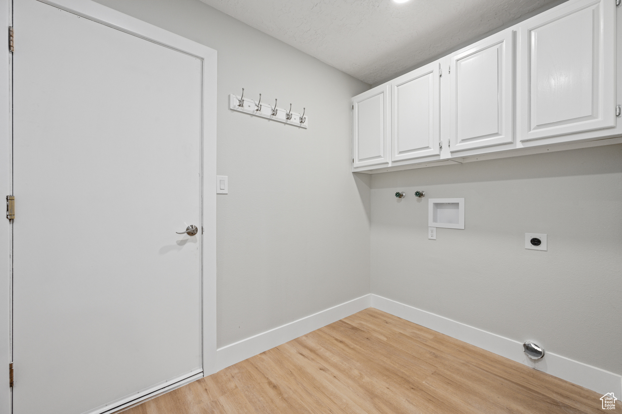 Laundry area with hookup for a gas dryer, cabinets, electric dryer hookup, light wood-type flooring, and hookup for a washing machine