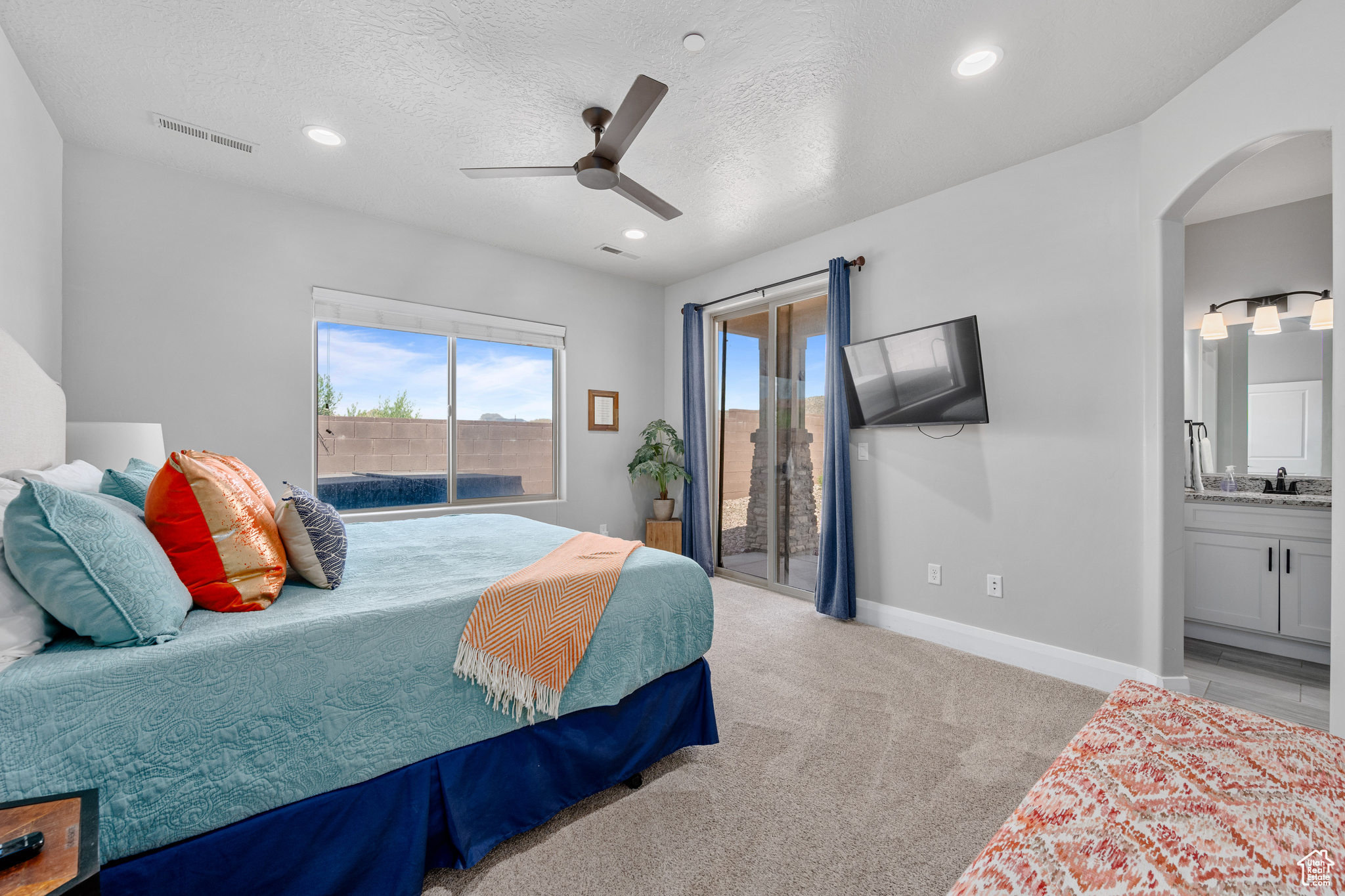 Bedroom featuring access to outside, ceiling fan, light carpet, connected bathroom, and a textured ceiling