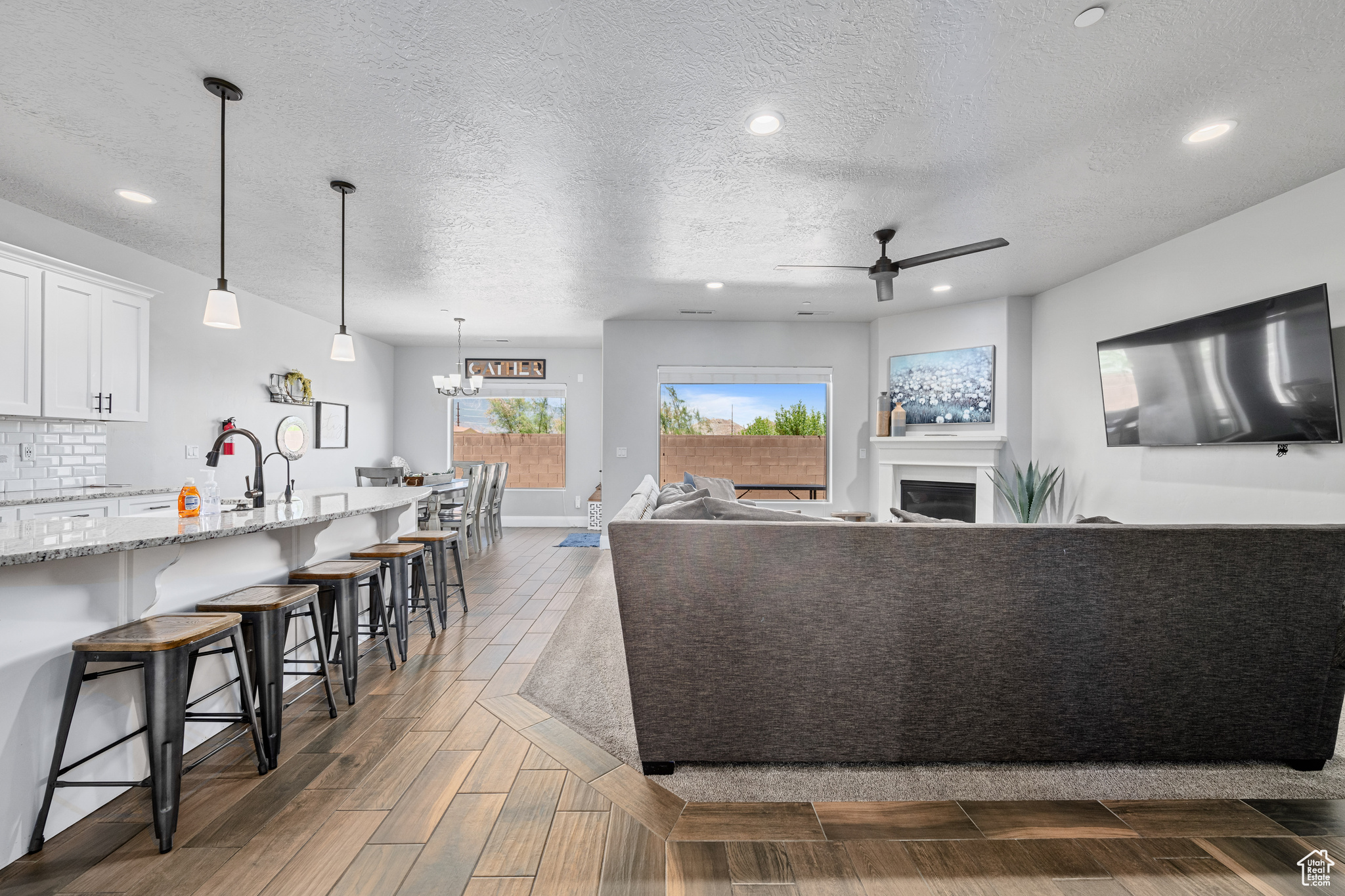 Living room with sink, hardwood / wood-style flooring, a textured ceiling, and ceiling fan with notable chandelier