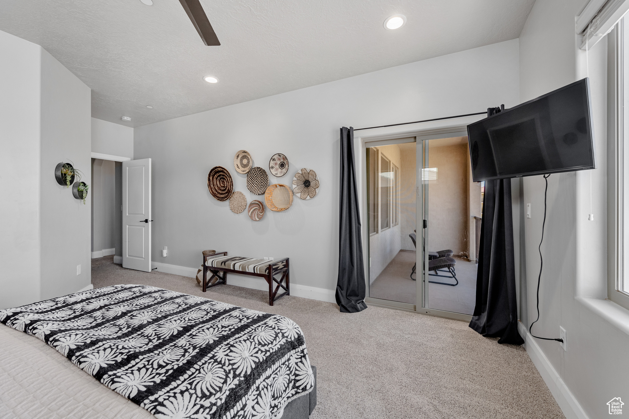 Bedroom featuring light carpet, ceiling fan, and multiple windows