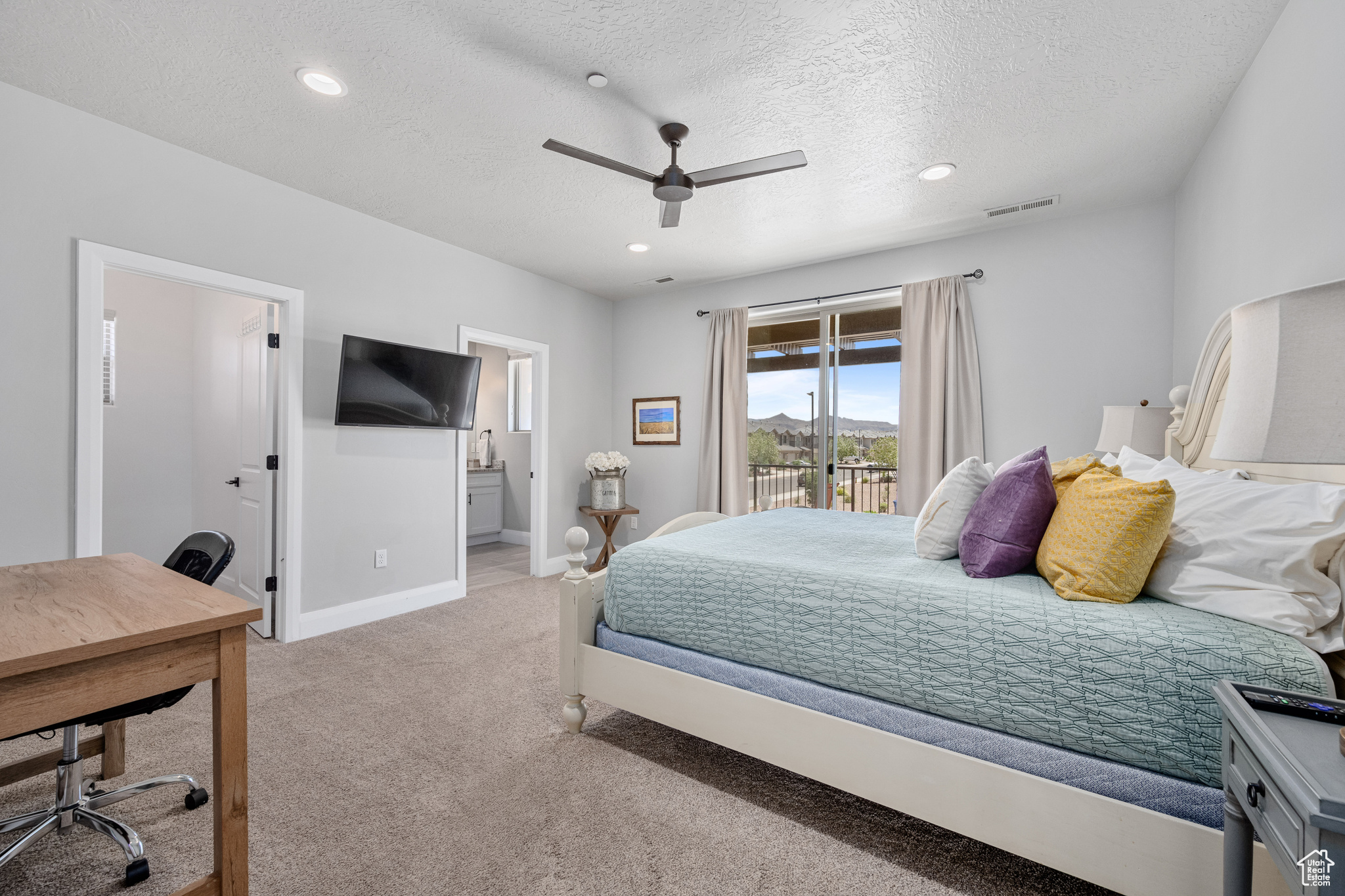 Bedroom with a textured ceiling, access to exterior, ensuite bathroom, ceiling fan, and light colored carpet