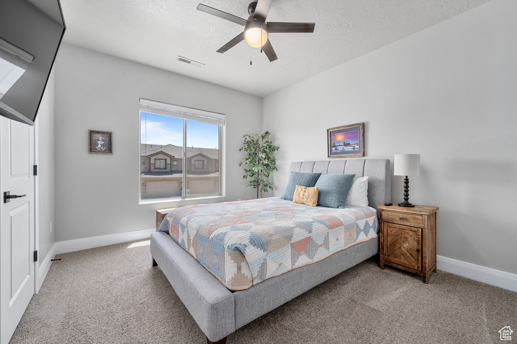 Carpeted bedroom featuring ceiling fan and a textured ceiling