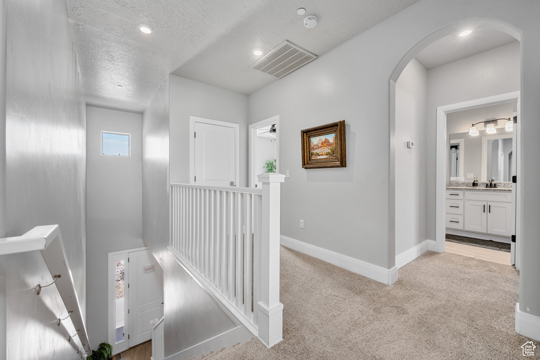 Hallway with light carpet, sink, and a textured ceiling