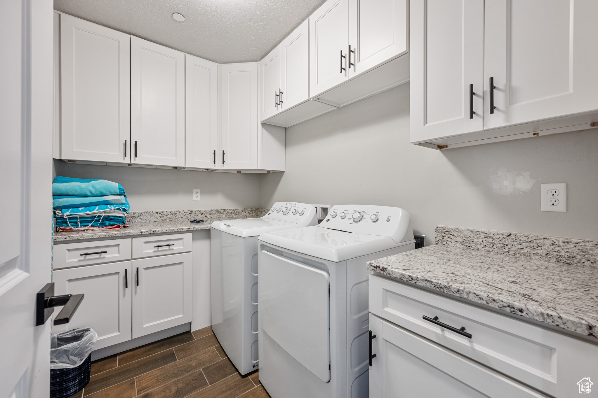 Laundry area featuring dark wood-type flooring, independent washer and dryer, a textured ceiling, and cabinets