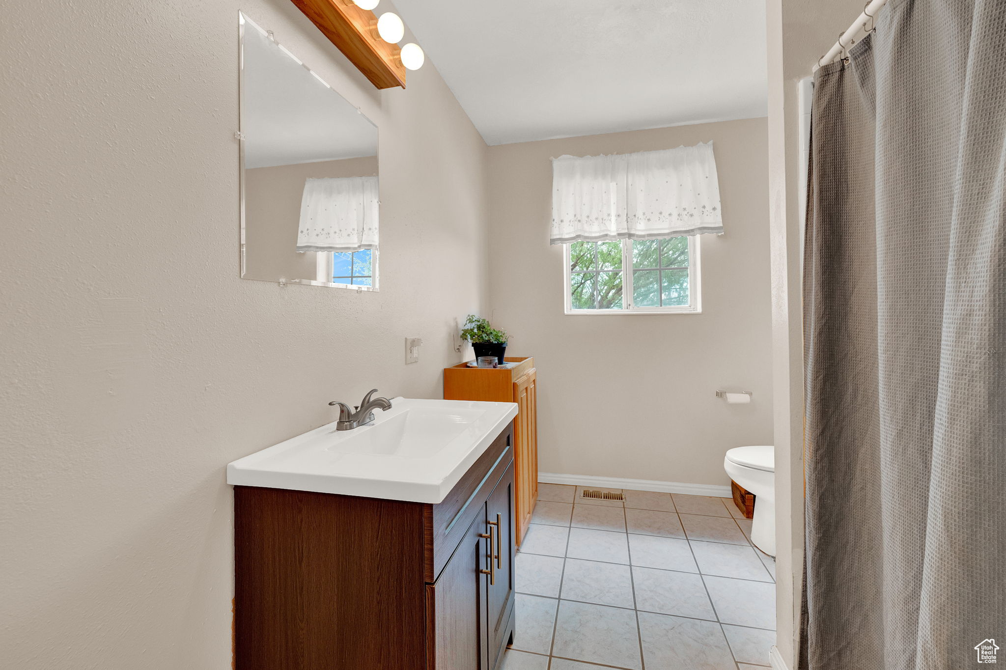 Bathroom featuring vanity, toilet, a wealth of natural light, and tile patterned flooring