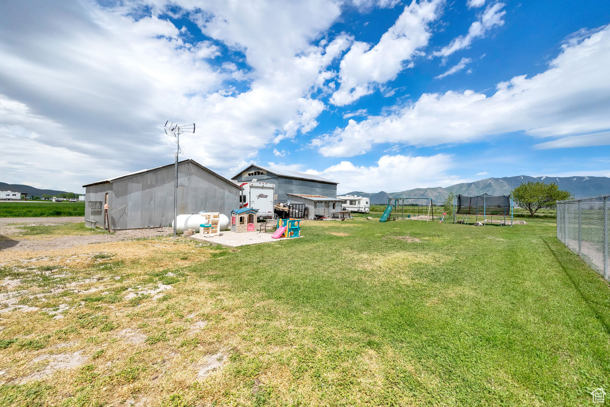 View of yard featuring a mountain view, a trampoline, a playground, and an outdoor structure