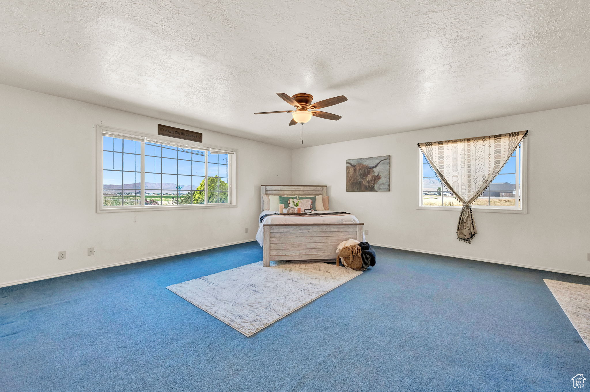 Unfurnished bedroom featuring dark colored carpet, a textured ceiling, and ceiling fan