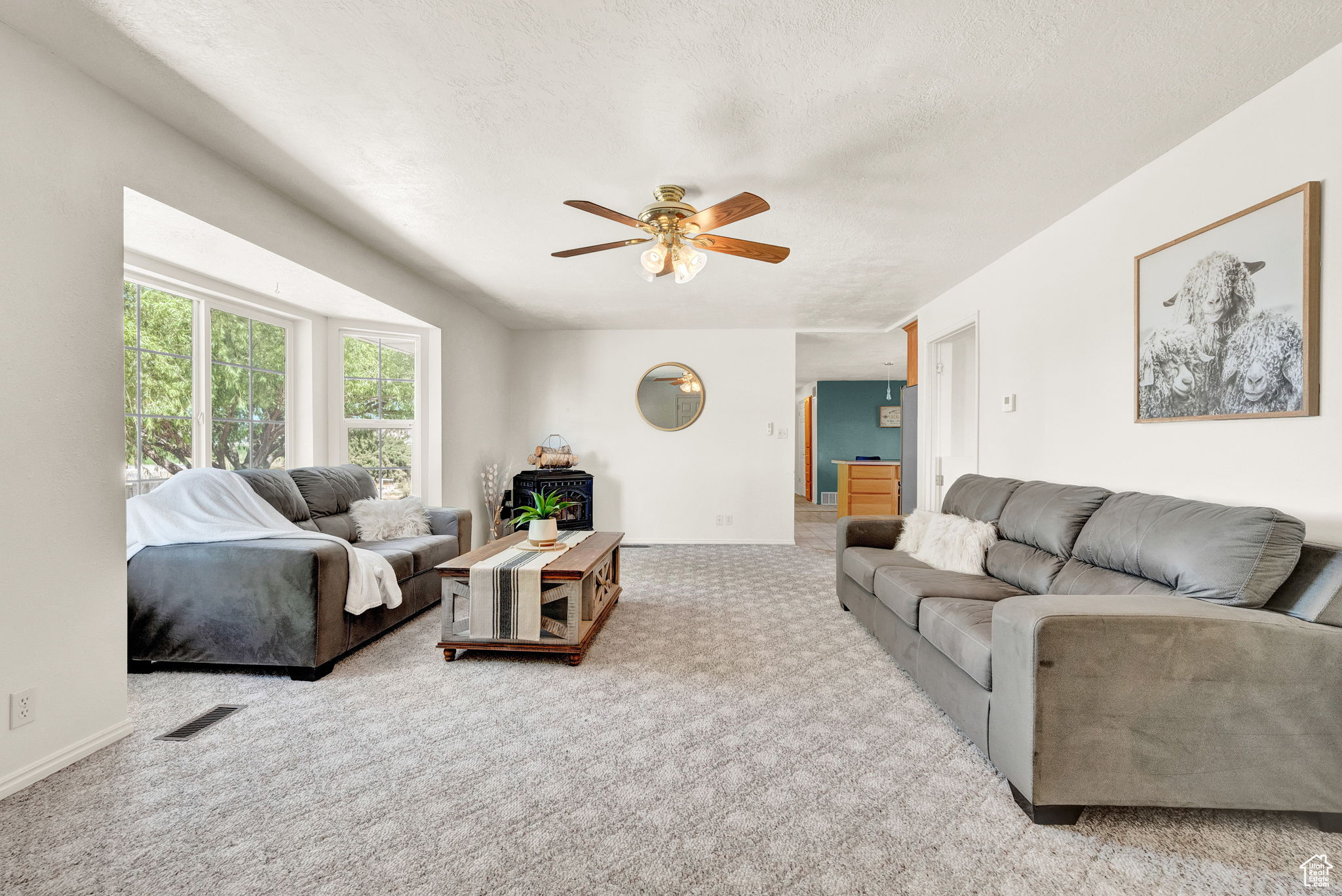 Carpeted living room featuring a textured ceiling and ceiling fan