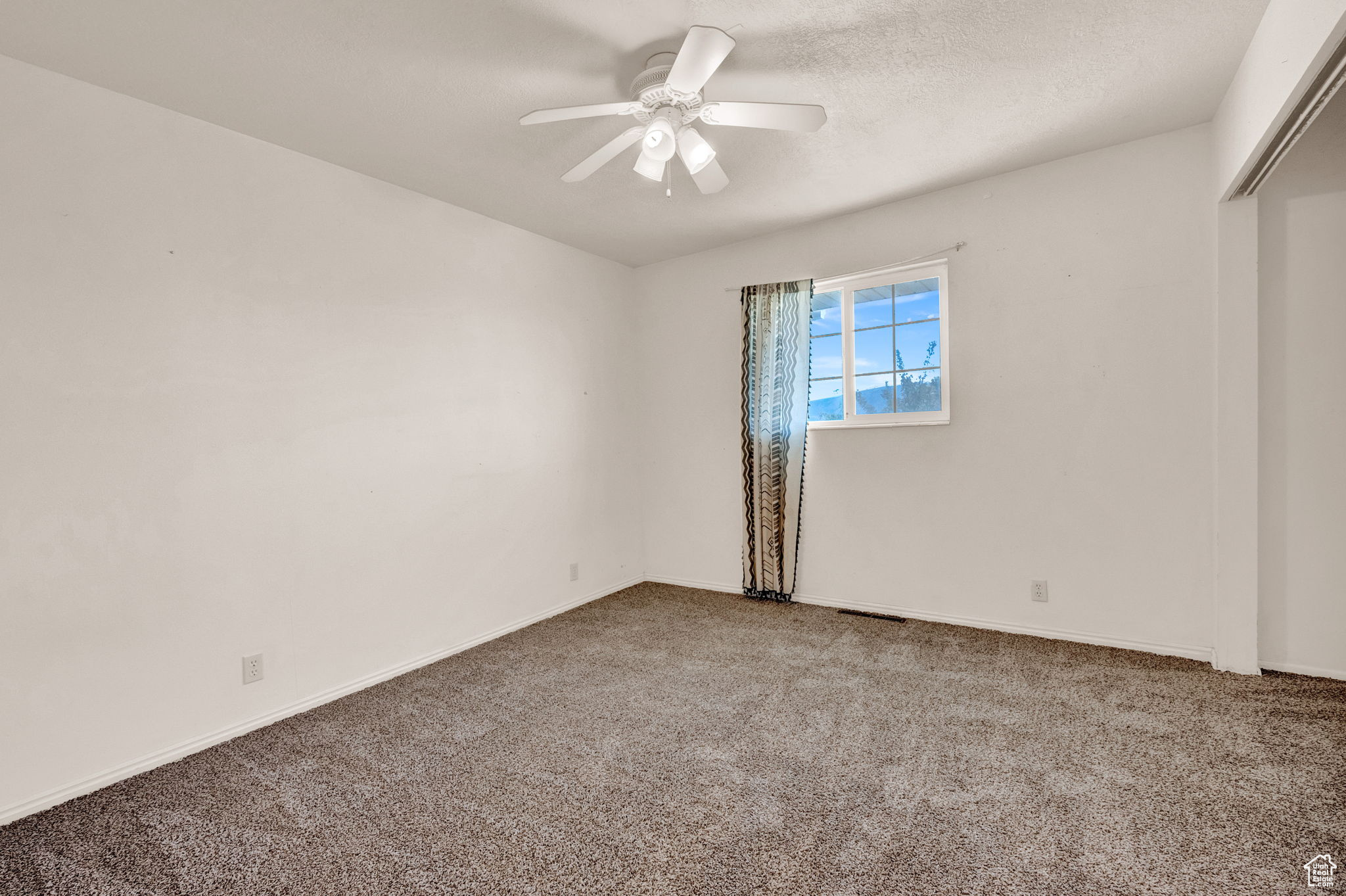 Unfurnished room featuring carpet flooring and ceiling fan