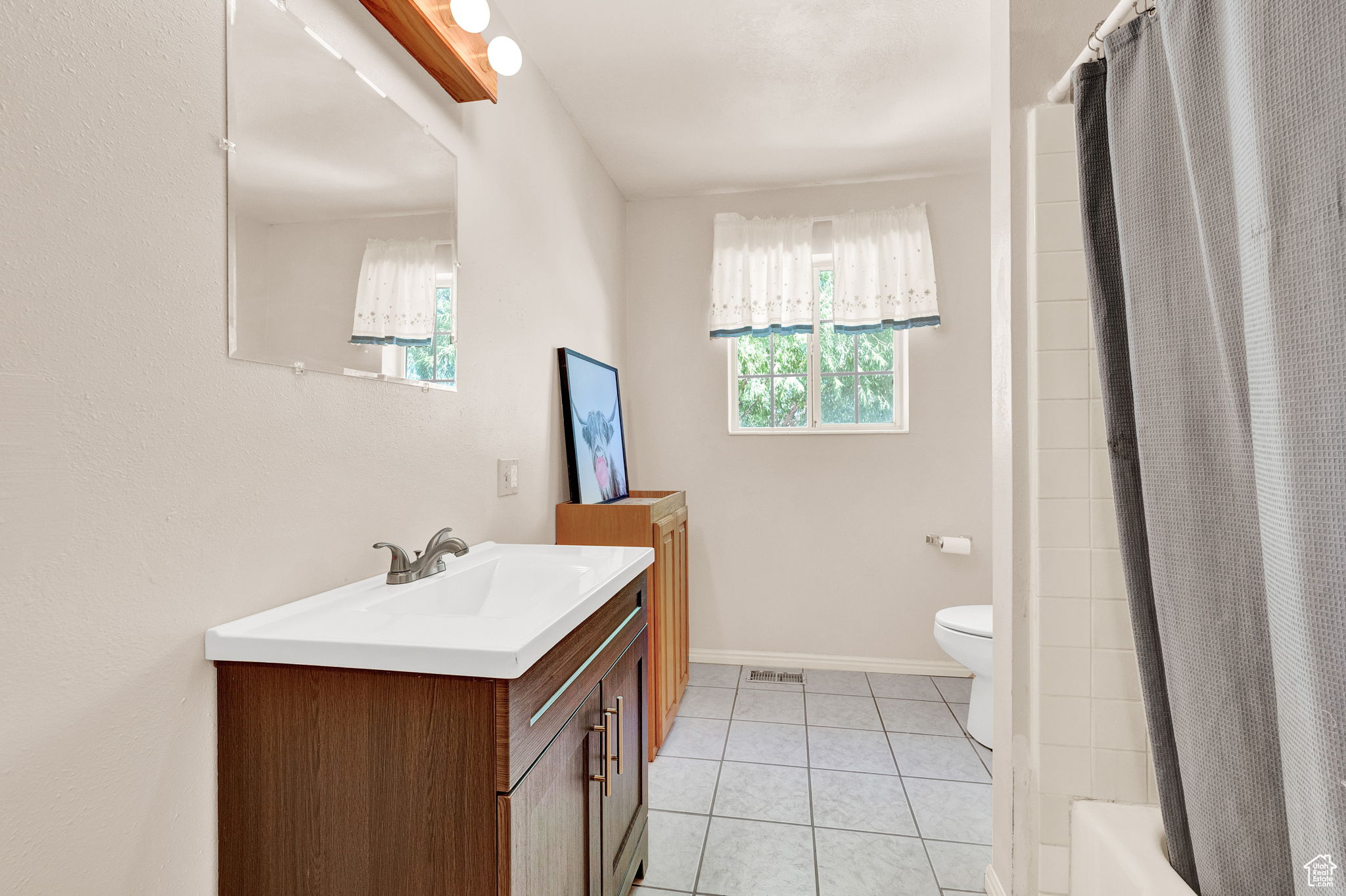 Full bathroom with tile patterned flooring, shower / bath combo, toilet, and vanity