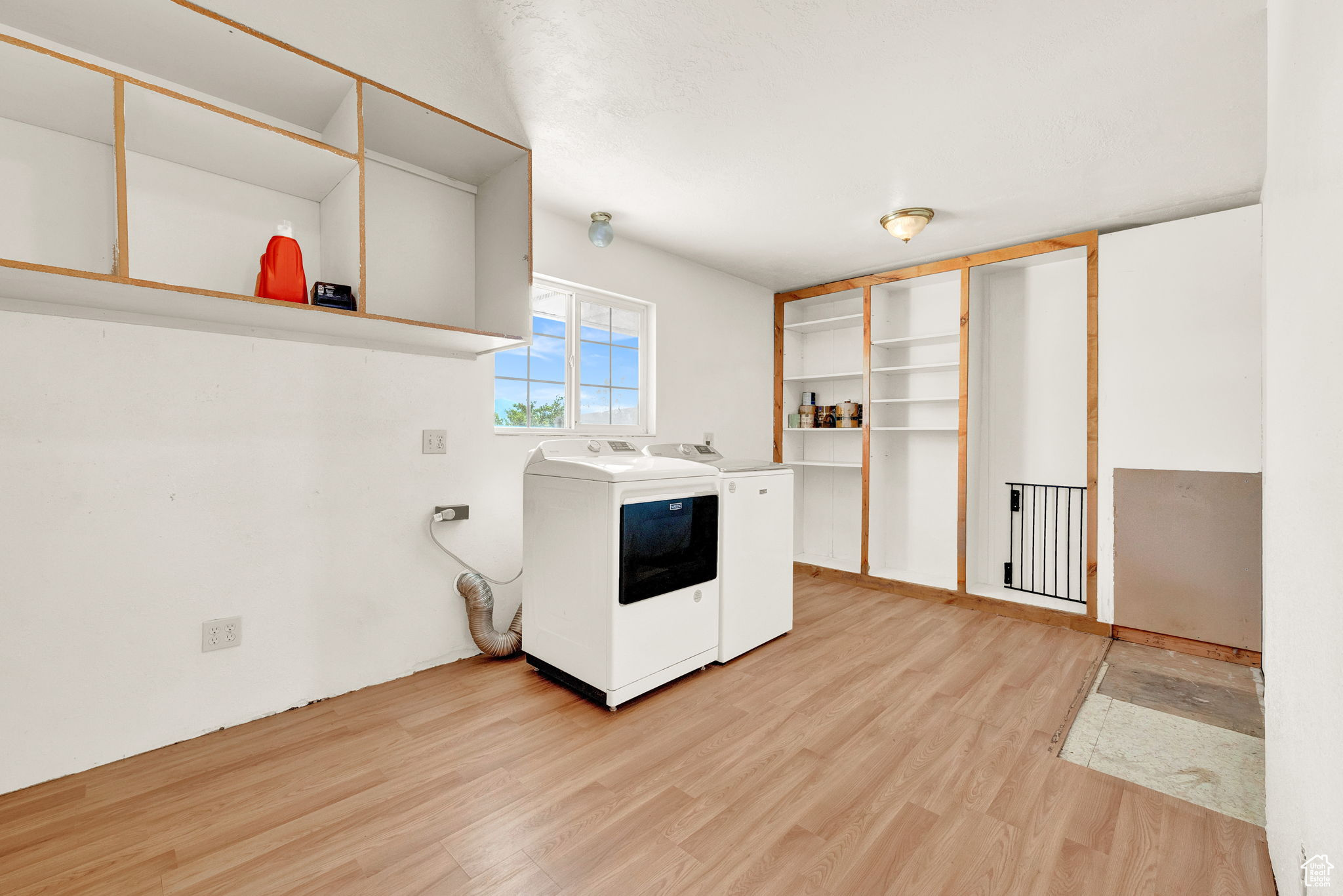 Interior space featuring light hardwood / wood-style flooring, washer and clothes dryer, and white cabinets