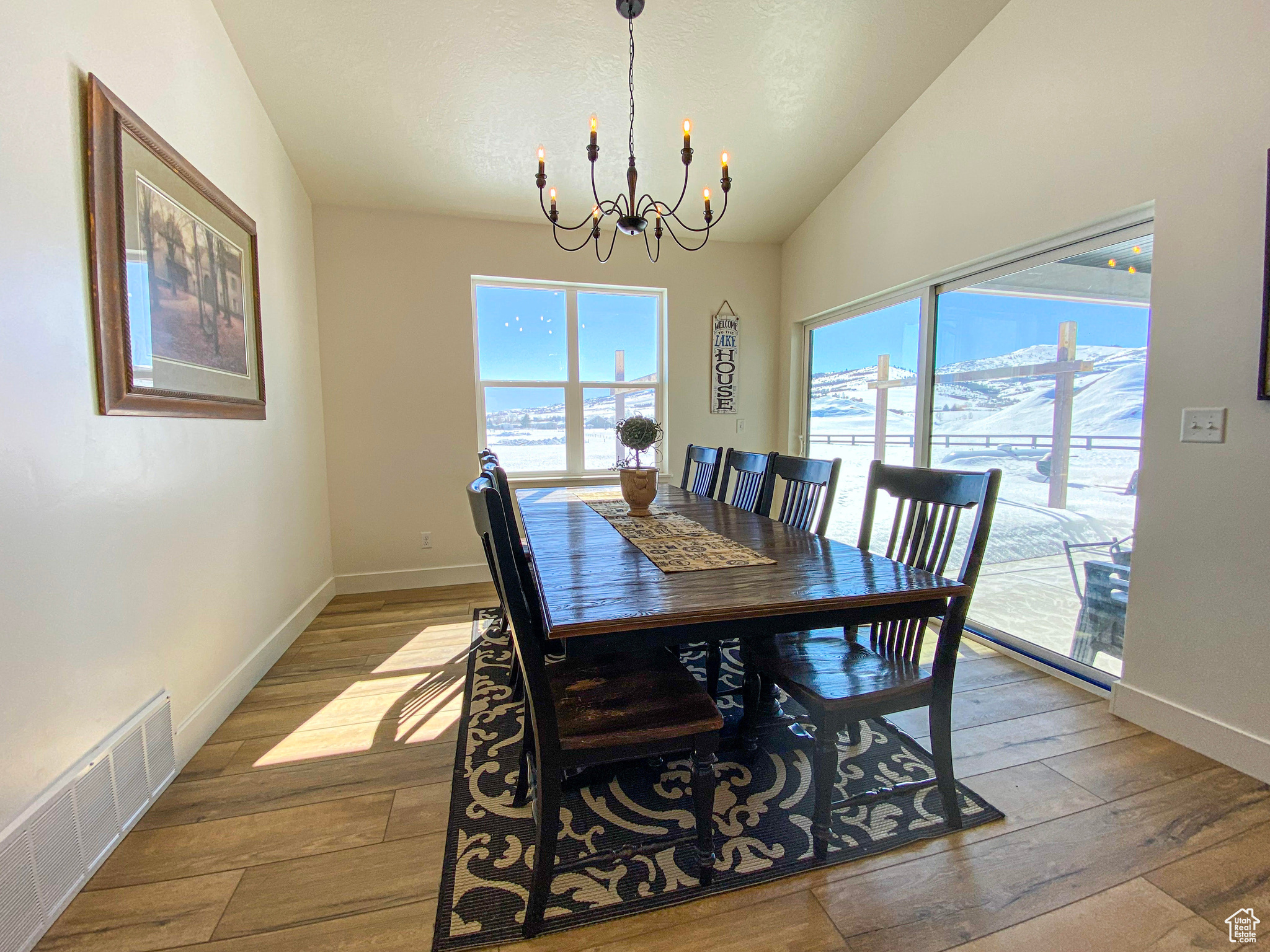 Dining room with a notable chandelier, vaulted ceiling, and hardwood / wood-style flooring