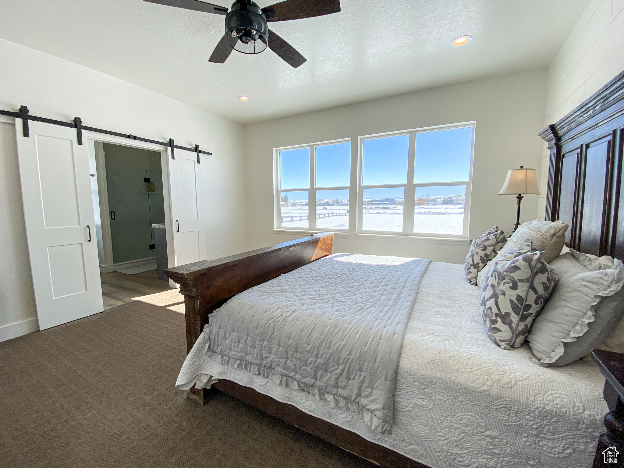 Master bedroom with carpet, a barn door, ceiling fan, and a textured ceiling