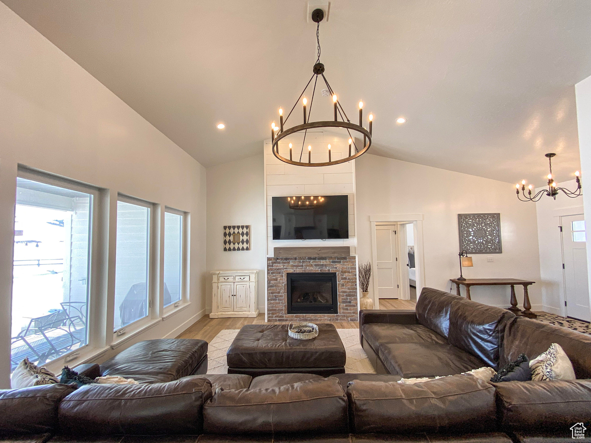 Living room with a healthy amount of sunlight, hardwood / wood-style flooring, vaulted ceiling, and an inviting chandelier