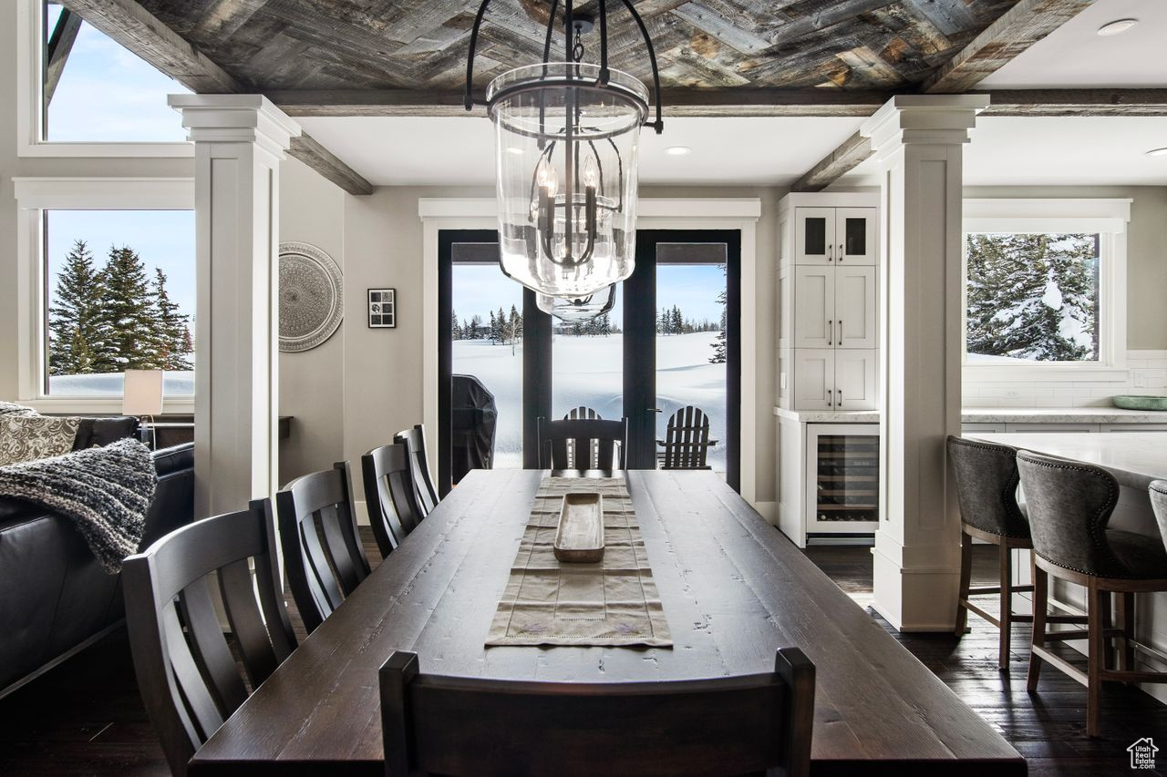 Dining space featuring a chandelier, dark hardwood / wood-style floors, ornate columns, and wine cooler