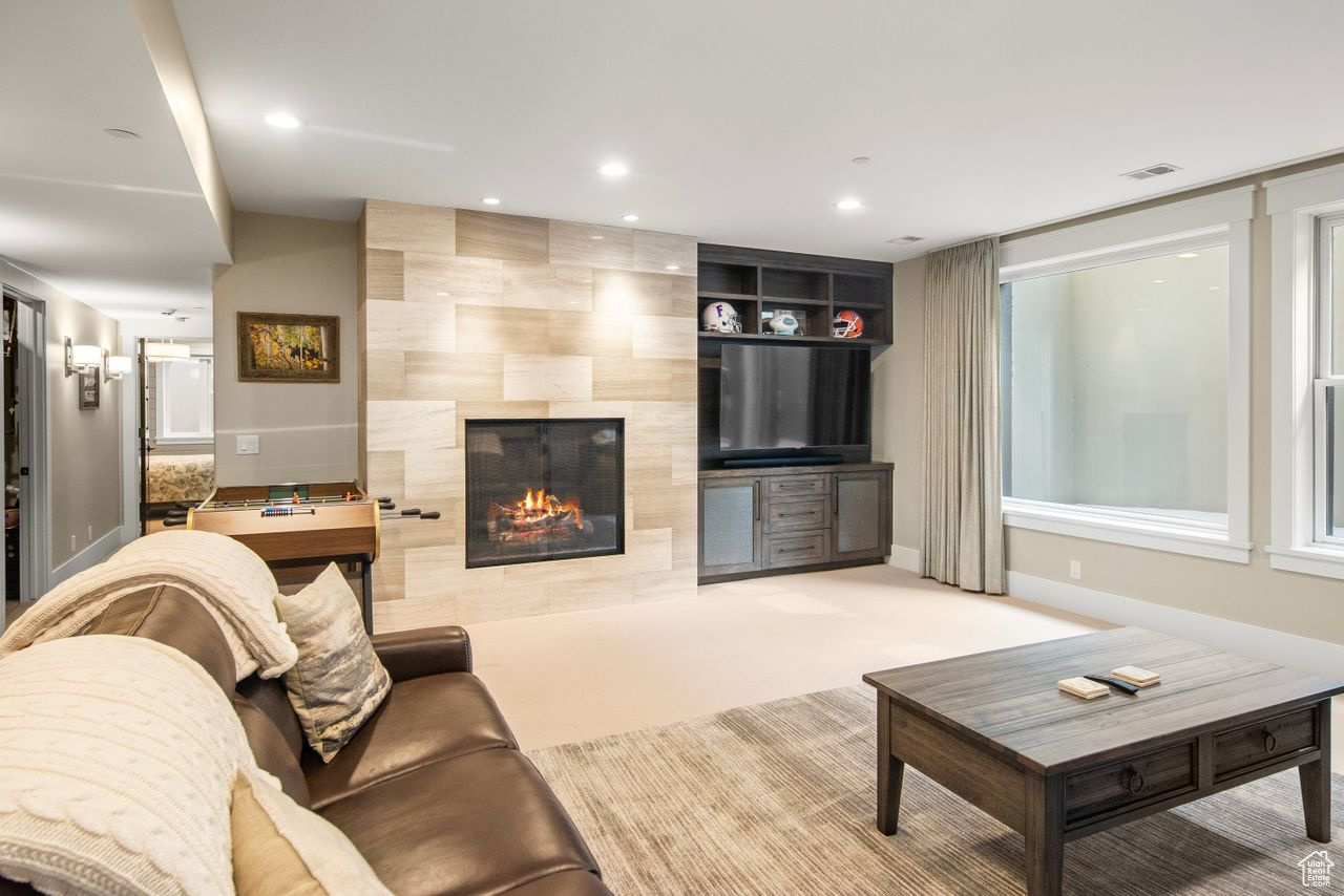 Living room featuring a fireplace, light colored carpet, and tile walls