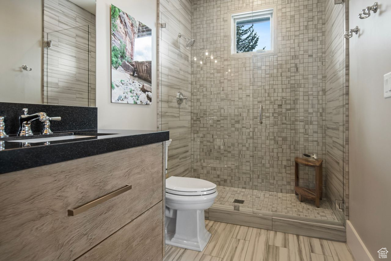 Bathroom with tile flooring, an enclosed shower, vanity, and toilet