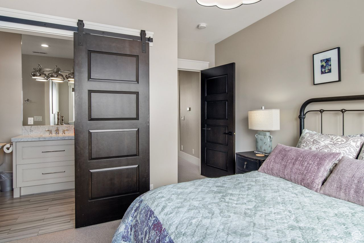 Carpeted bedroom featuring a barn door and sink