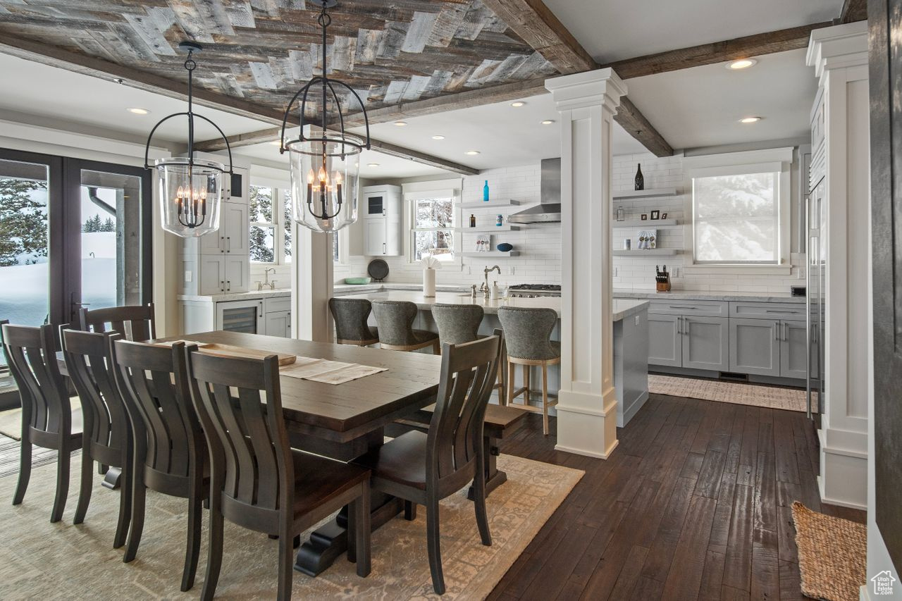 Dining space with sink, dark hardwood / wood-style flooring, an inviting chandelier, and decorative columns