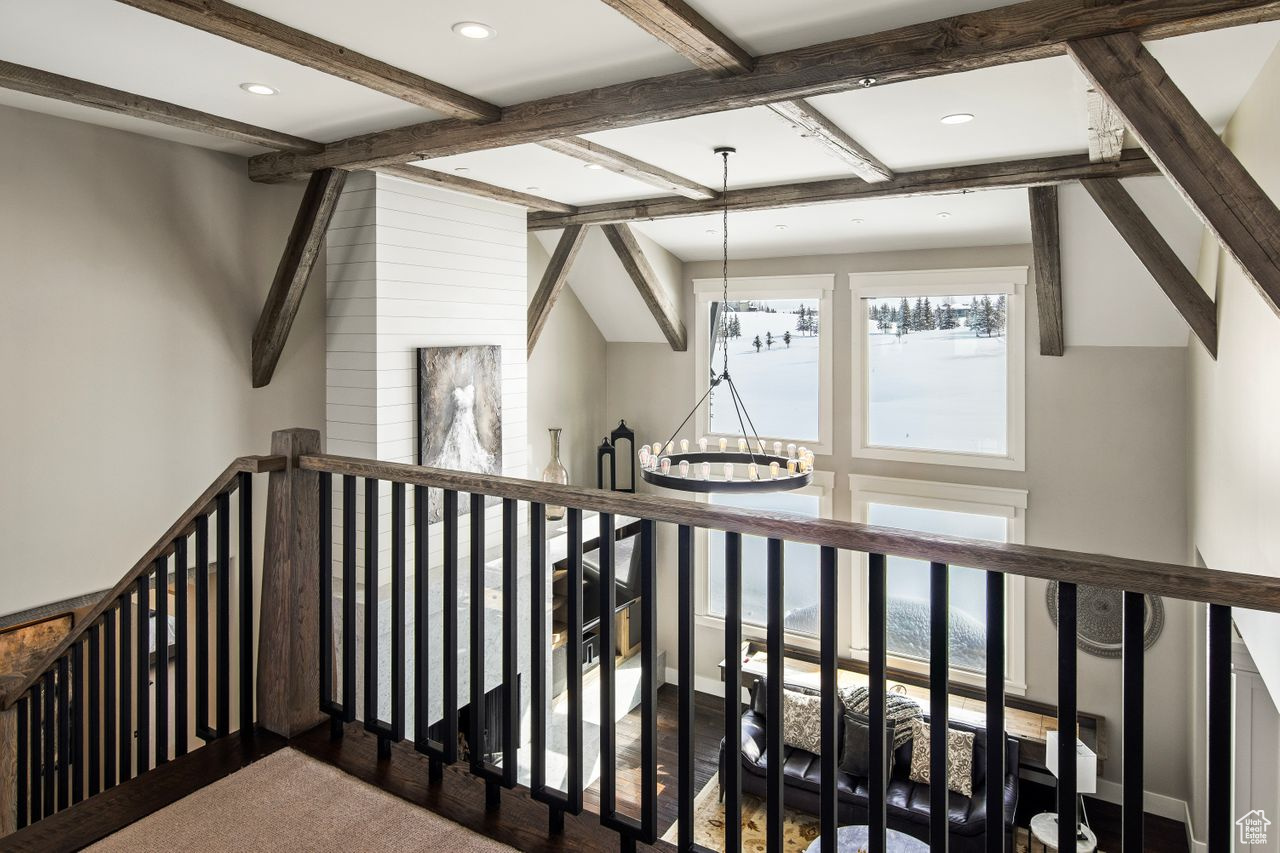 Staircase with a notable chandelier and beamed ceiling