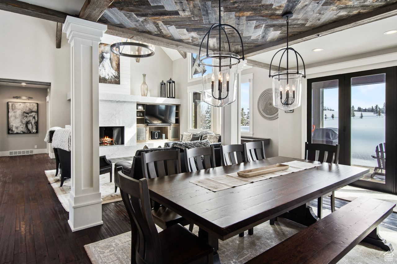 Dining space with a healthy amount of sunlight, dark hardwood / wood-style flooring, decorative columns, and a fireplace