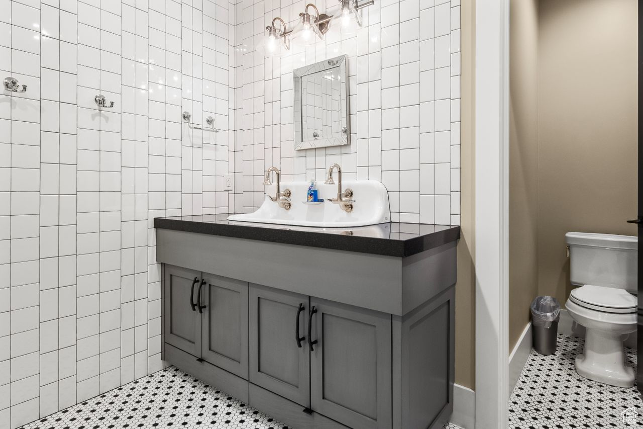 Bathroom featuring tile flooring, tile walls, toilet, and vanity