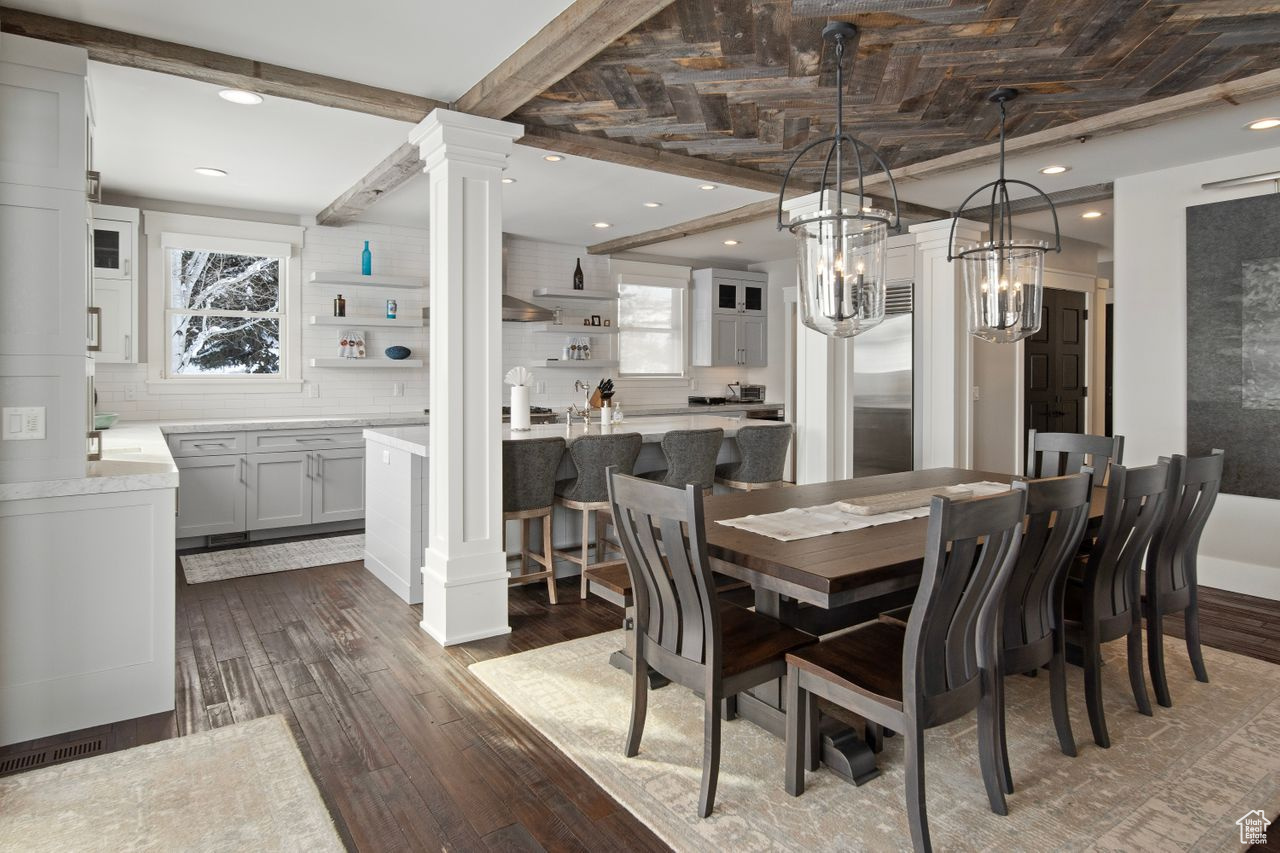 Dining space featuring a healthy amount of sunlight, ornate columns, and dark wood-type flooring