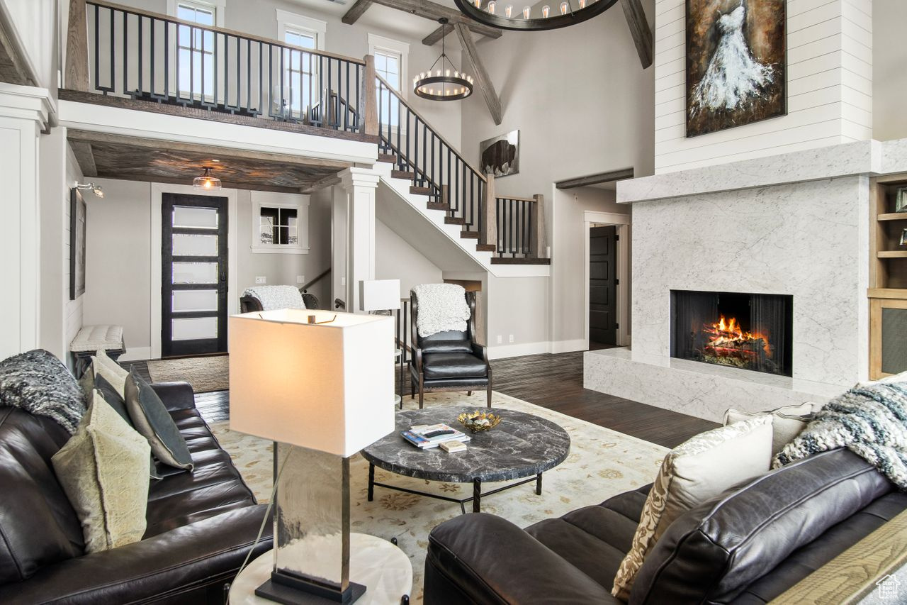 Living room with beamed ceiling, a high ceiling, a fireplace, and wood-type flooring