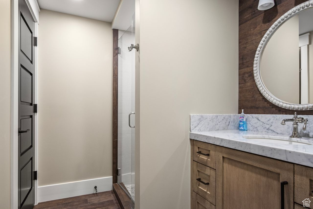 Bathroom featuring a shower with door, hardwood / wood-style floors, and vanity