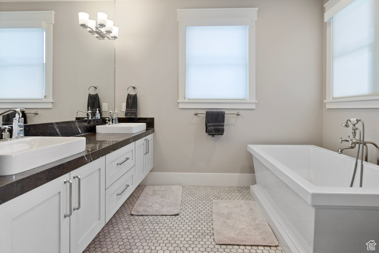 Bathroom featuring a healthy amount of sunlight, tile flooring, vanity with extensive cabinet space, and dual sinks