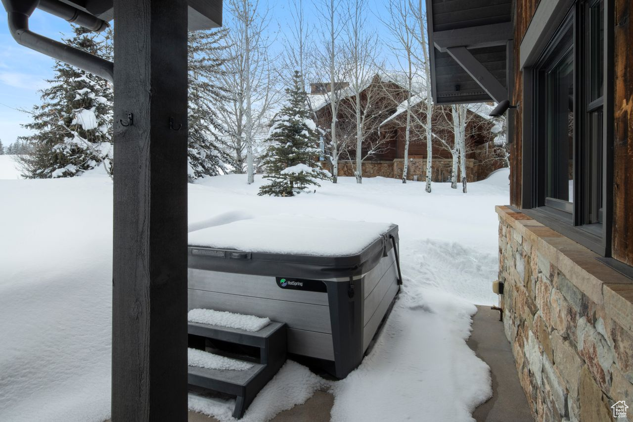 Yard layered in snow with a hot tub