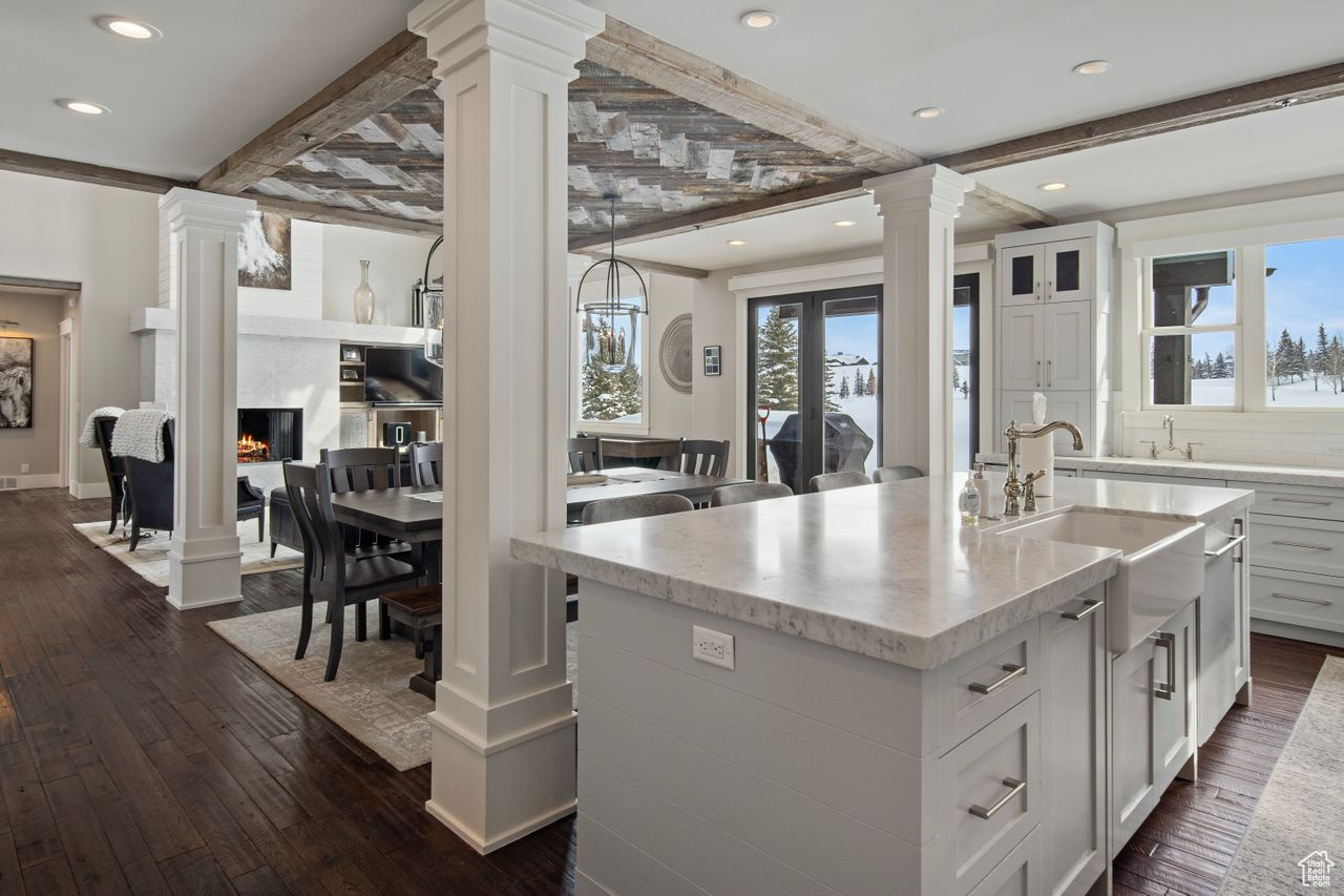 Kitchen with a high end fireplace, a center island with sink, dark hardwood / wood-style flooring, and white cabinetry