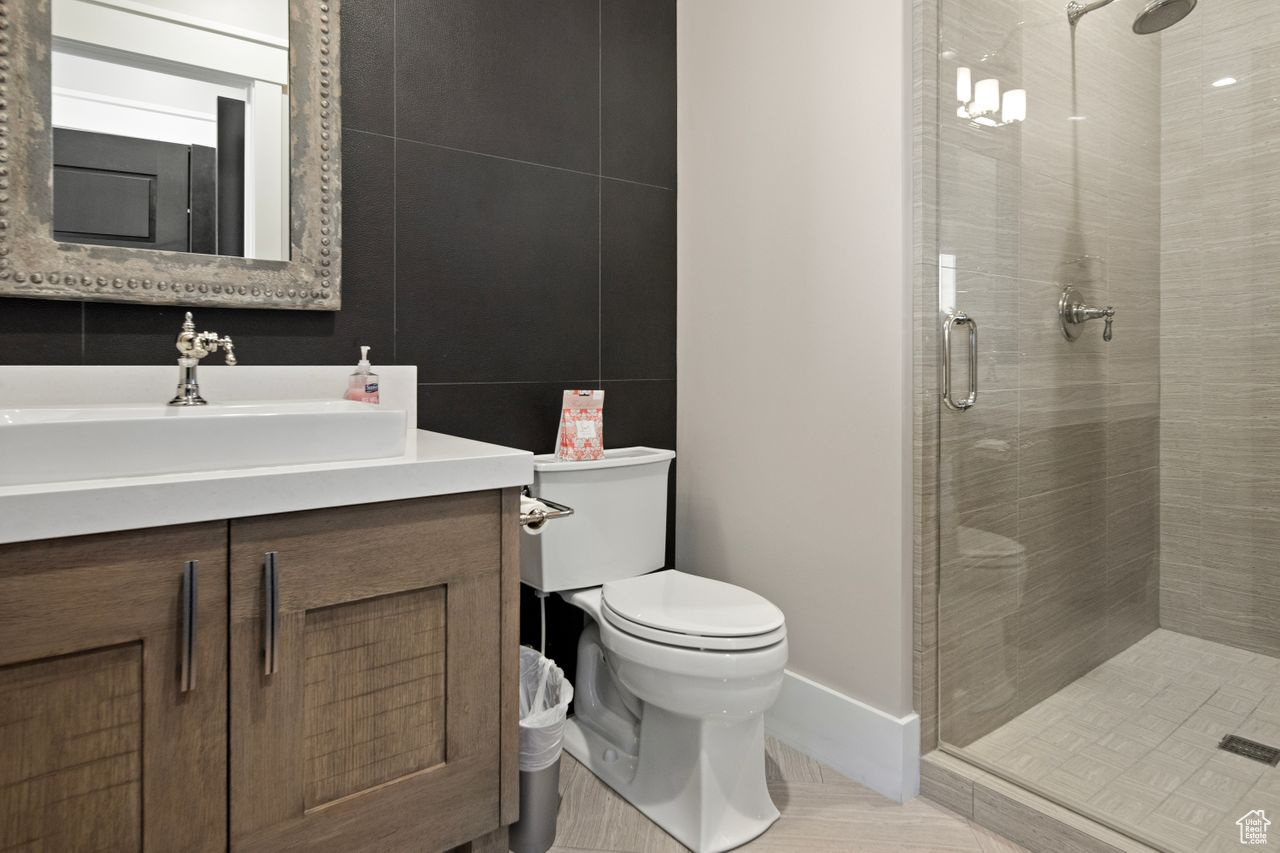 Bathroom with a shower with shower door, vanity, and toilet