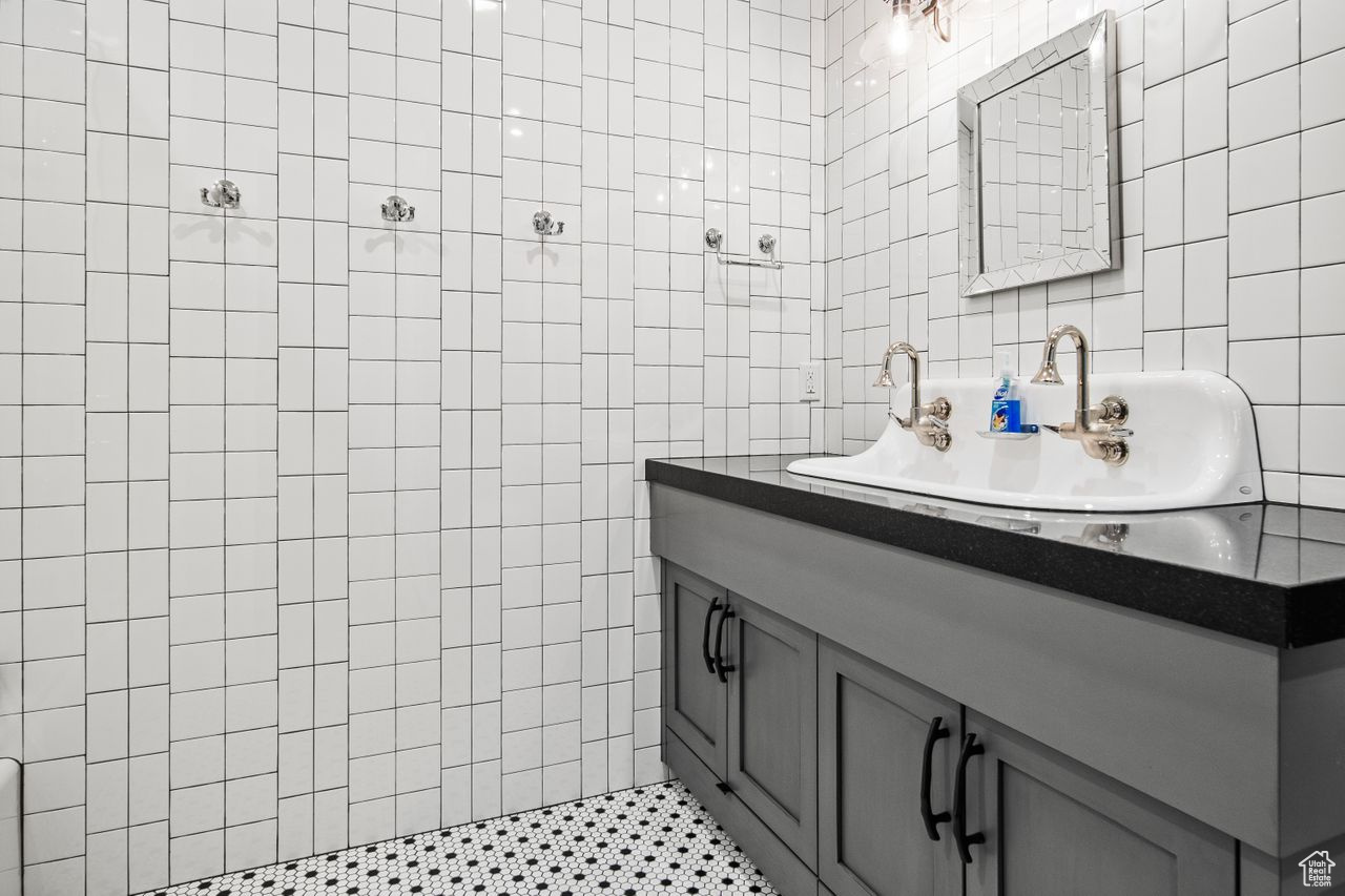 Bathroom with vanity with extensive cabinet space, tiled shower, and tile walls