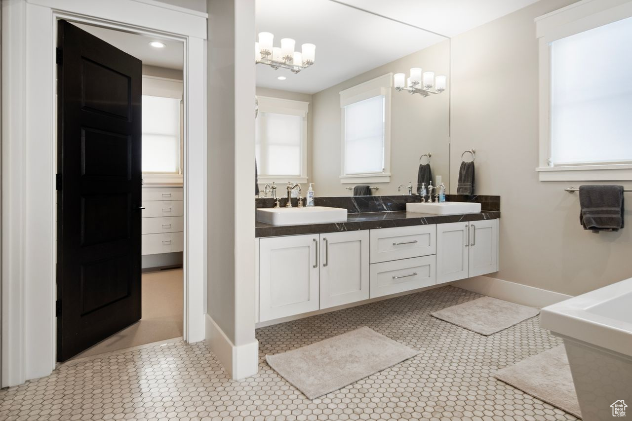 Bathroom featuring a notable chandelier, tile flooring, oversized vanity, and double sink