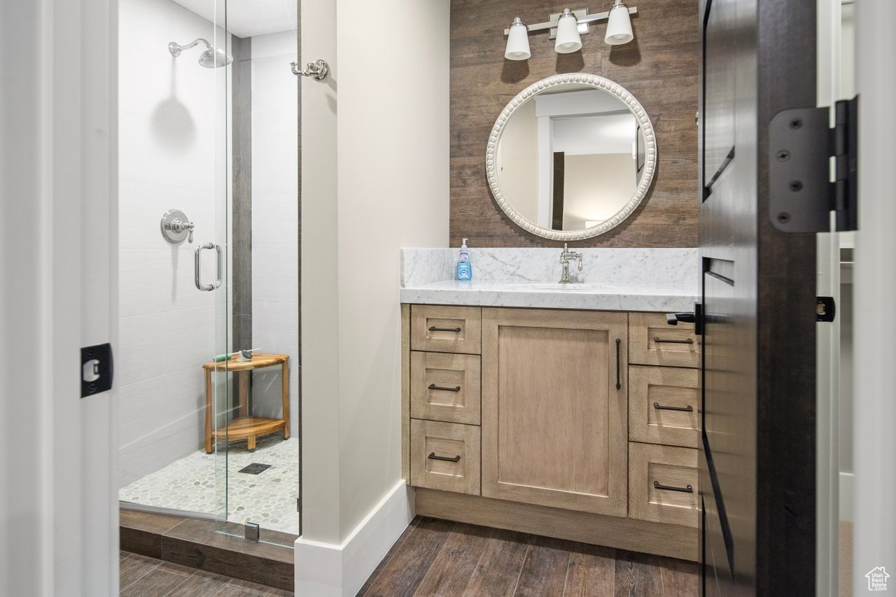 Bathroom featuring walk in shower, hardwood / wood-style flooring, and large vanity