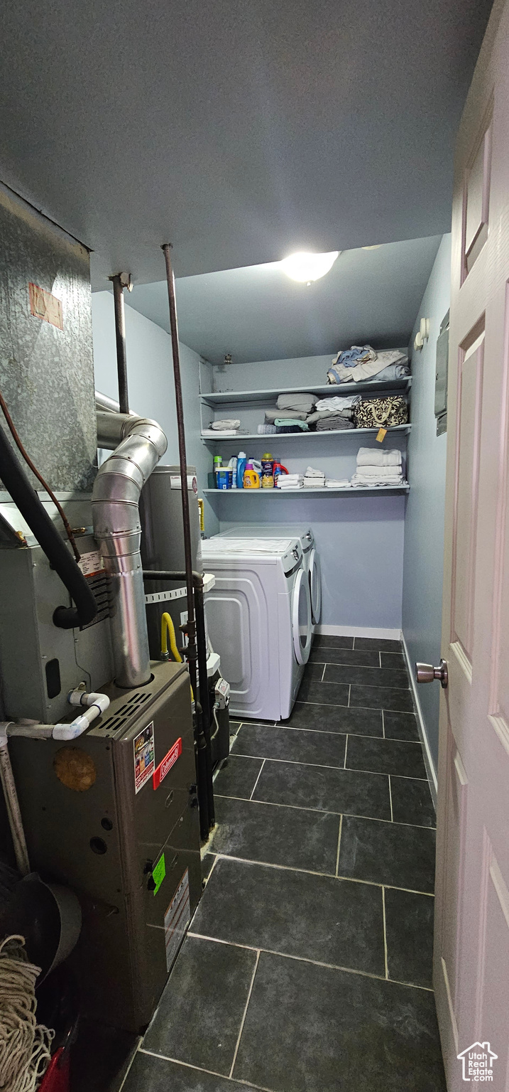 Laundry area featuring washer and clothes dryer and dark tile floors