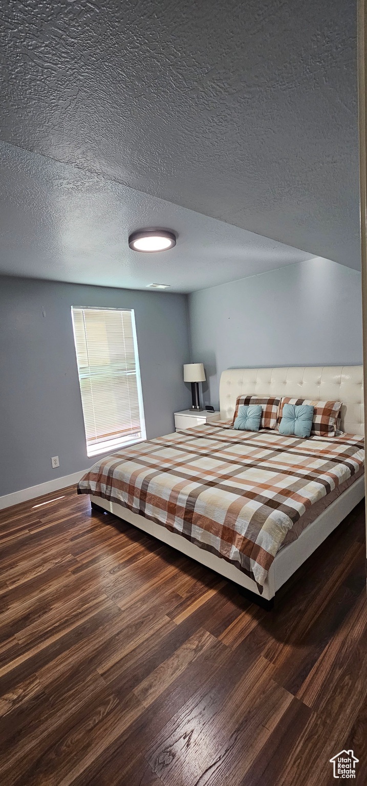 Bedroom featuring dark wood-type flooring and a textured ceiling