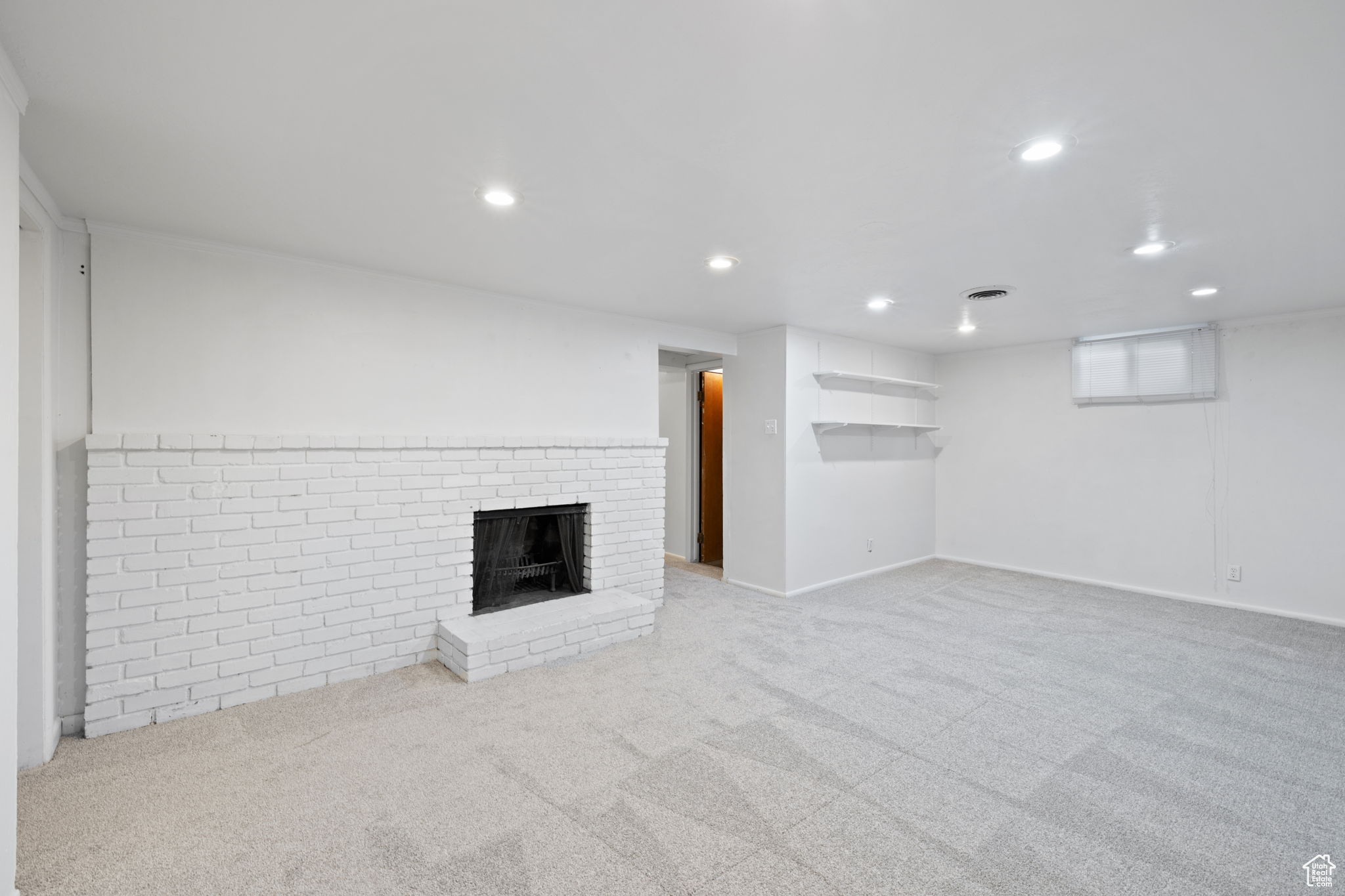 Unfurnished living room with carpet floors and a brick fireplace