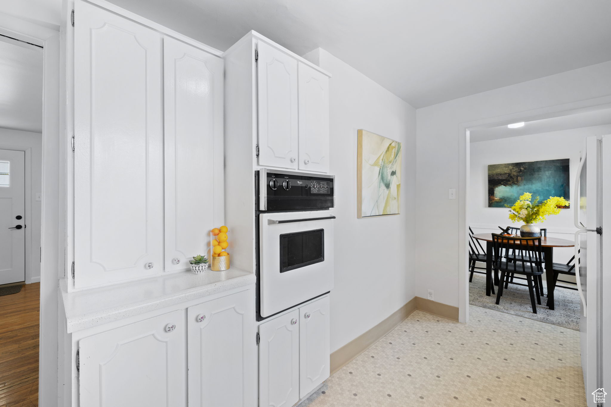 Kitchen featuring white appliances, white cabinetry, and light hardwood / wood-style flooring