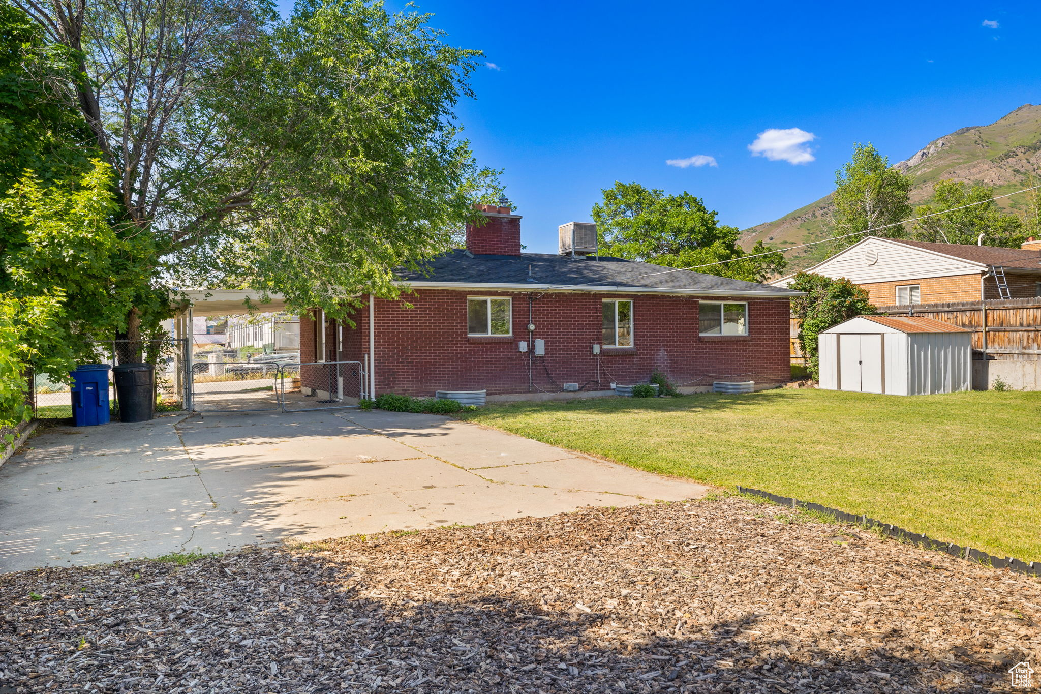 Back of property featuring a yard, a carport, a mountain view, and a shed