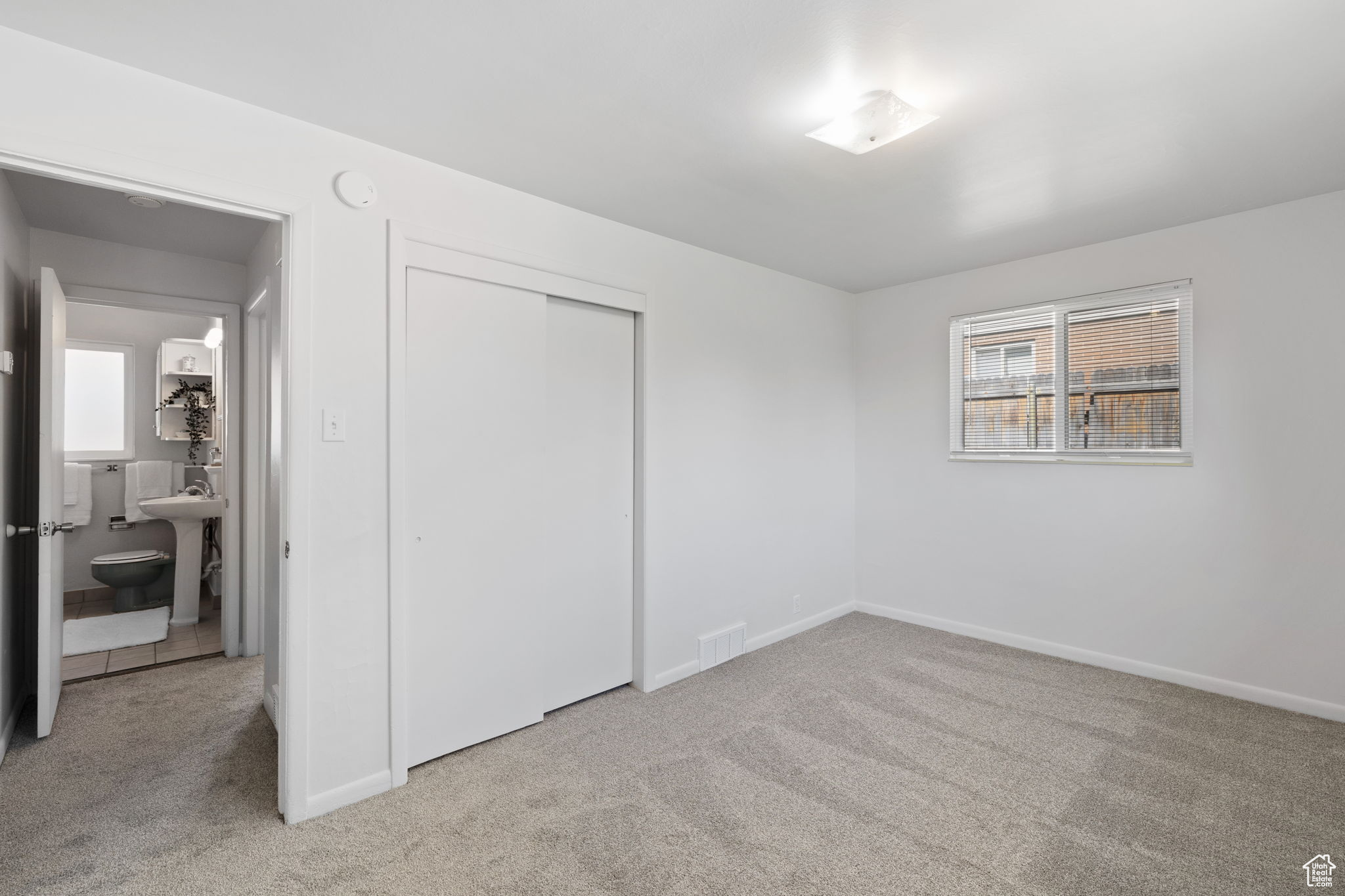 Unfurnished bedroom with carpet, sink, a closet, and ensuite bath