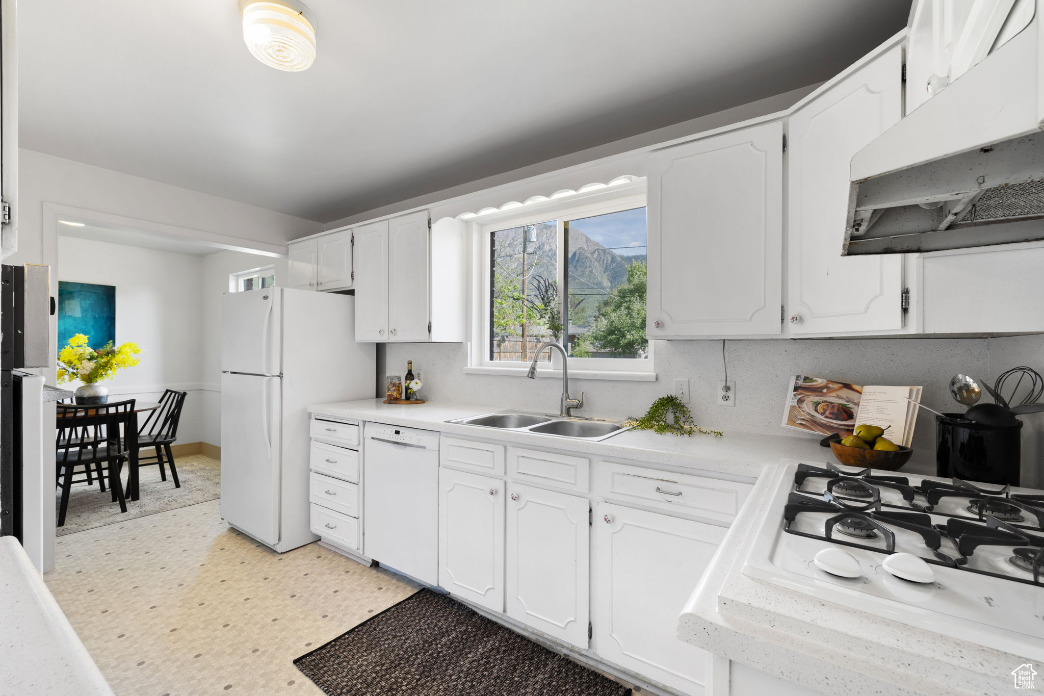 Kitchen with white appliances, sink, and white cabinetry