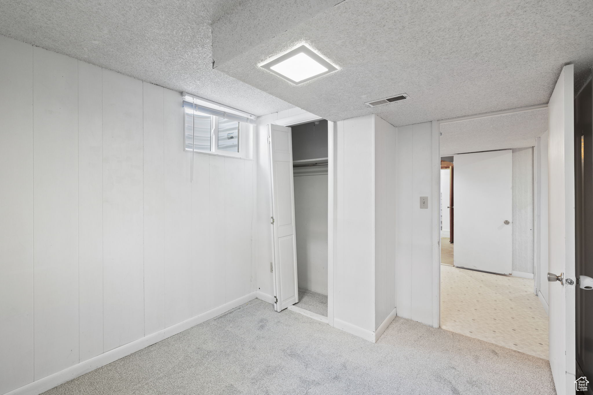 Basement with a textured ceiling and light carpet